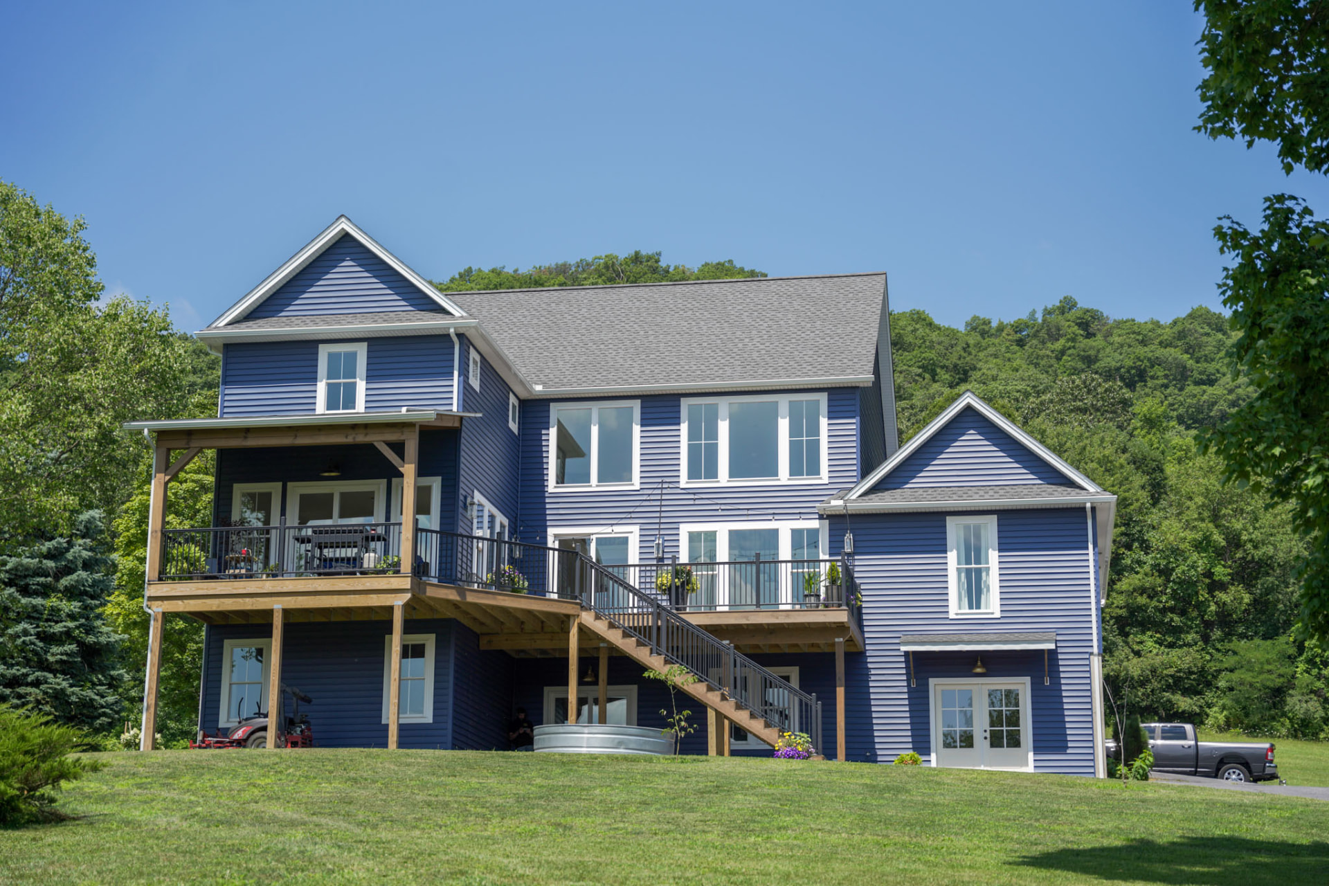 Byler Residence — full rear elevation of the blue custom home with timber decks, staircase, and walk-out lower level — KB Builders, Central Pennsylvania