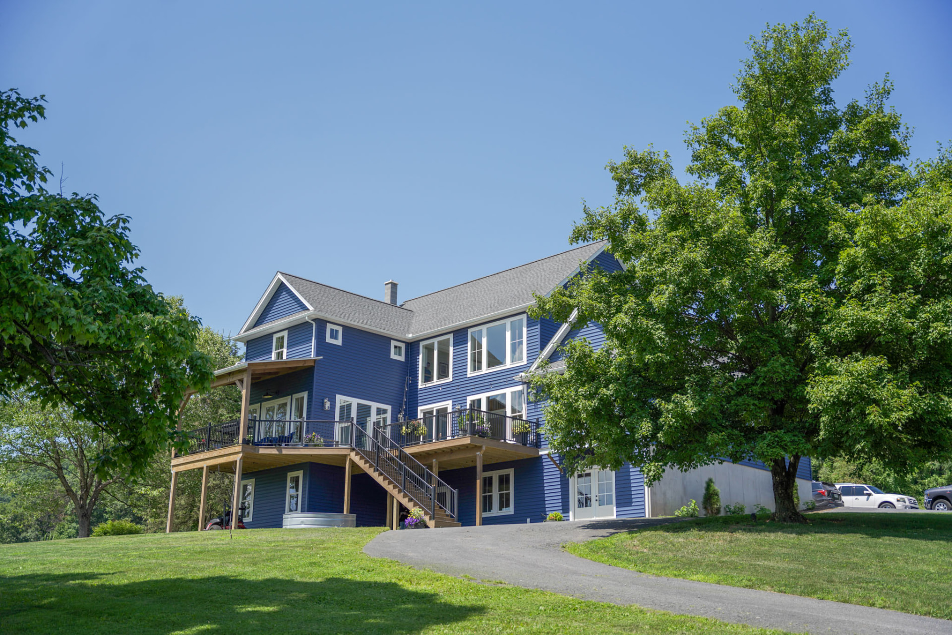 Byler Residence — rear view of the blue two-story home set against mature trees with a curved gravel drive — KB Builders, Central Pennsylvania