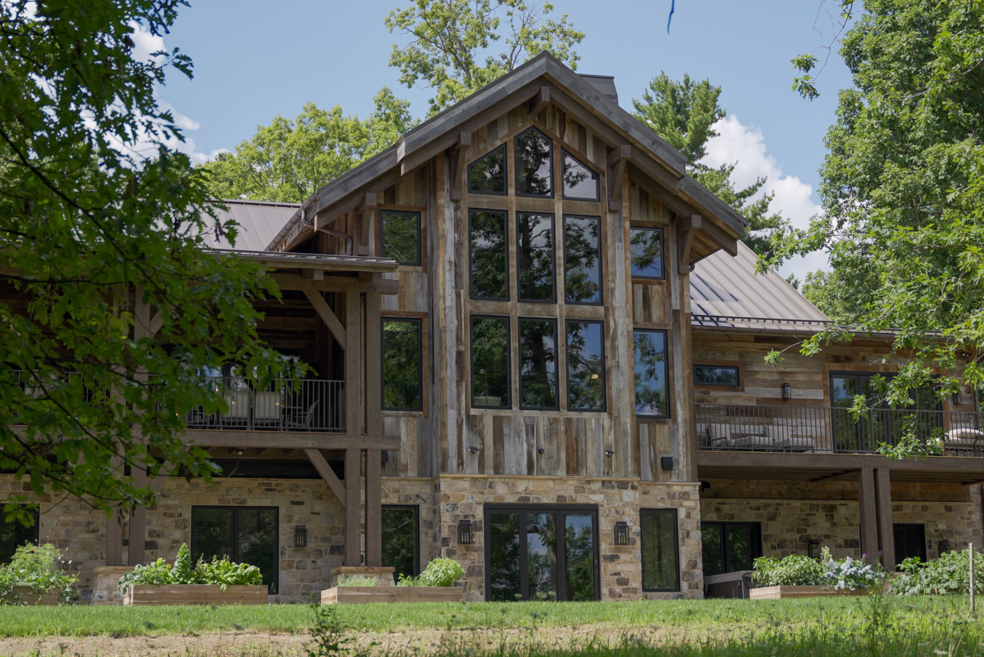 Wright Residence — two-story window wall beneath a reclaimed timber gable framed by mature trees — KB Builders, Central Pennsylvania