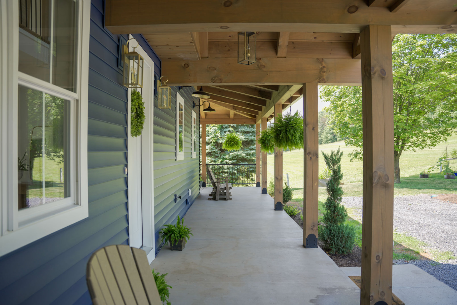 Byler Residence — covered front porch with timber posts, brass lanterns, and hanging ferns overlooking the valley — KB Builders, Central Pennsylvania