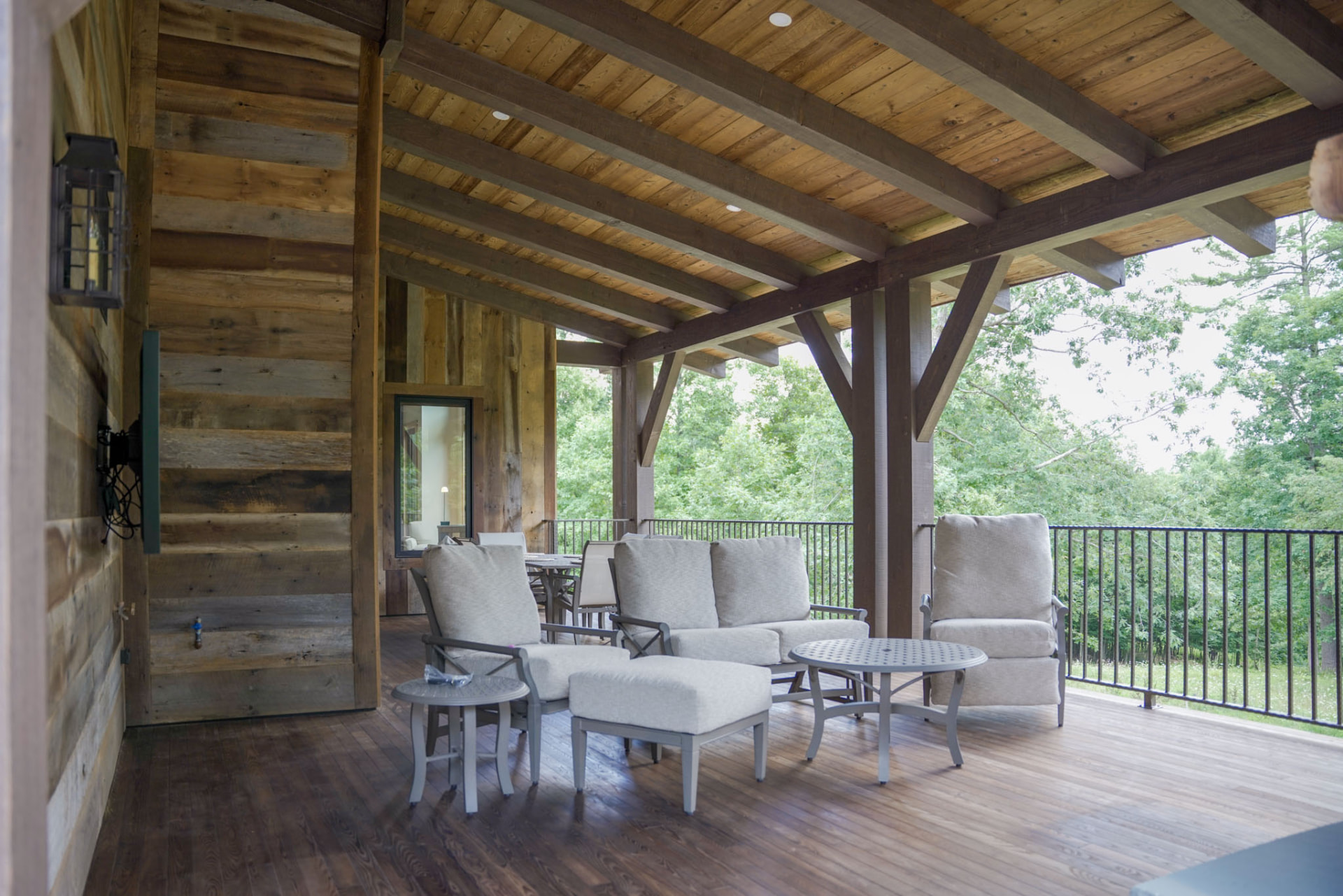 Wright Residence — covered deck lounge with reclaimed wood walls, timber beams, and forest views — KB Builders, Central Pennsylvania