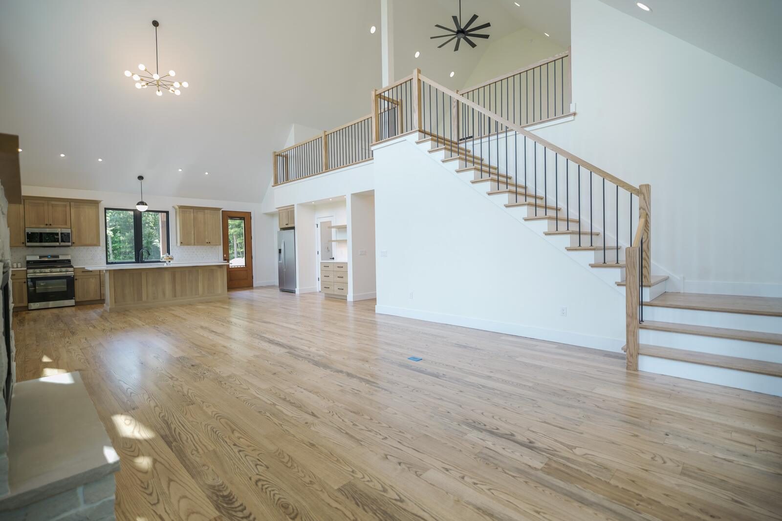 Open-concept great room with vaulted ceiling, loft overlook, and white-oak floors — custom home by KB Builders, Mifflintown, PA