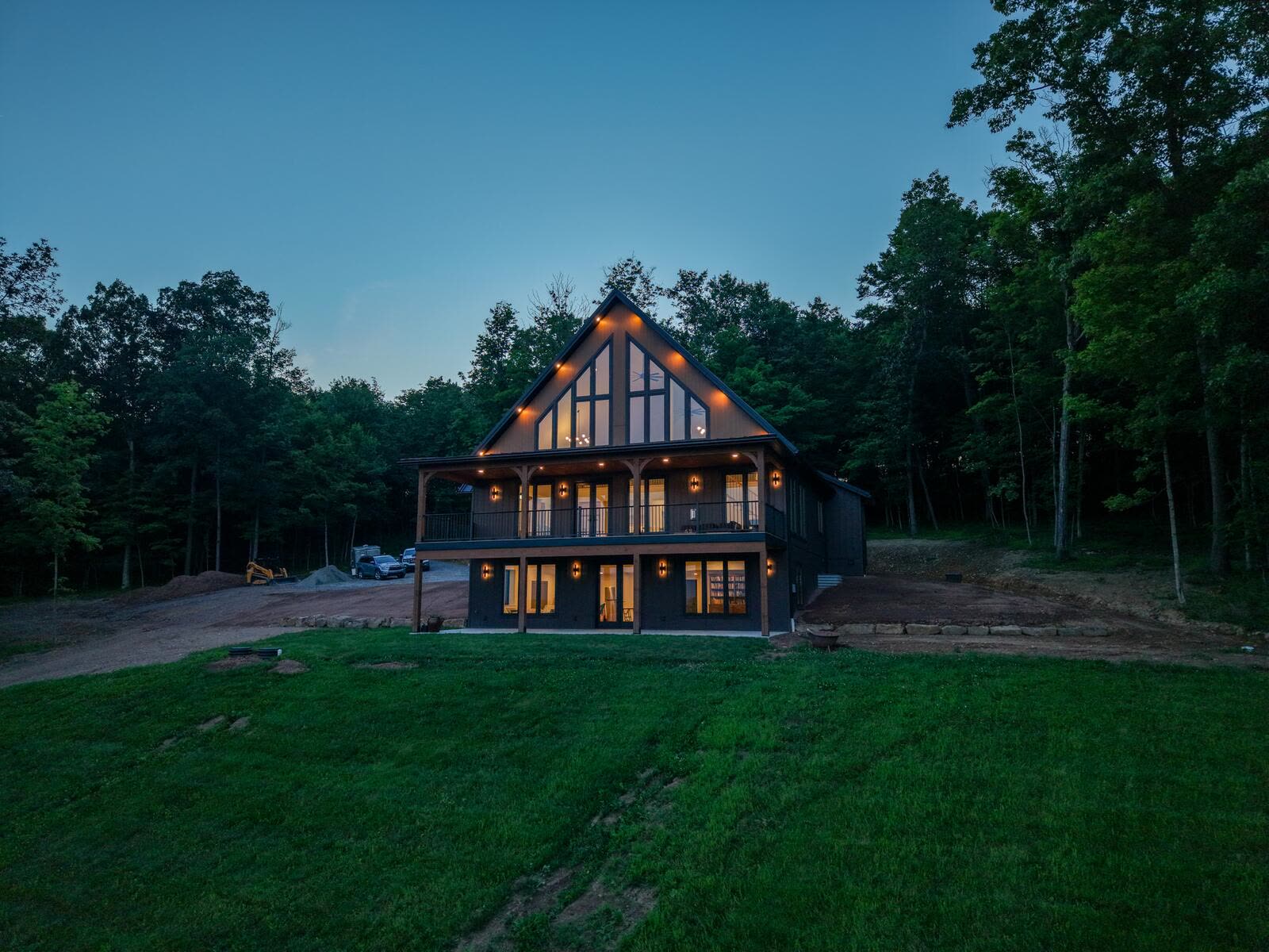 Rear view of the Shetler Residence at dusk with warm-lit gable windows framed by forest — KB Builders, Mifflintown, PA
