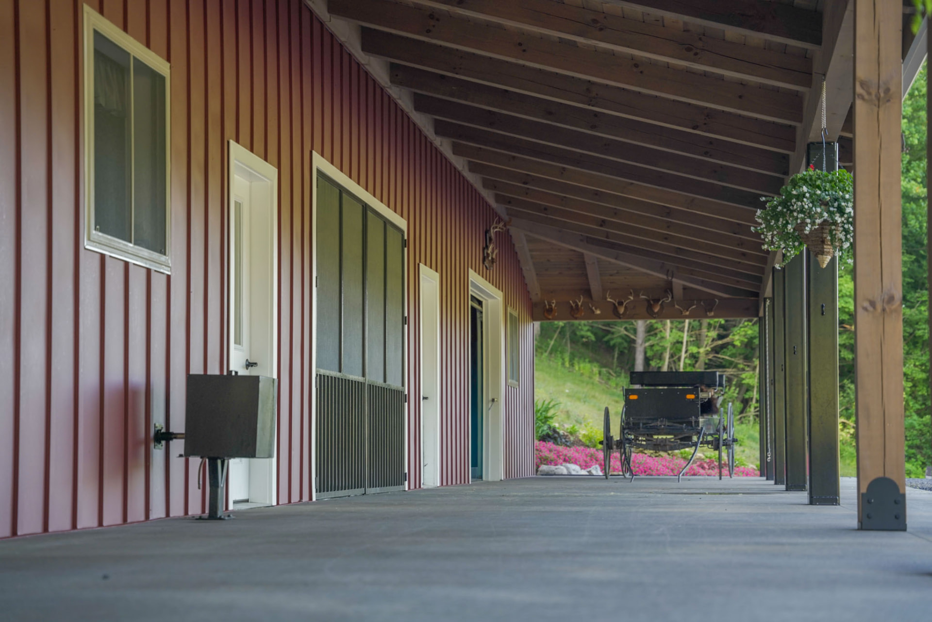 Peachy Residence — long covered concrete porch with timber posts, doors, and buggy parked at the far end — KB Builders, McVeytown, PA