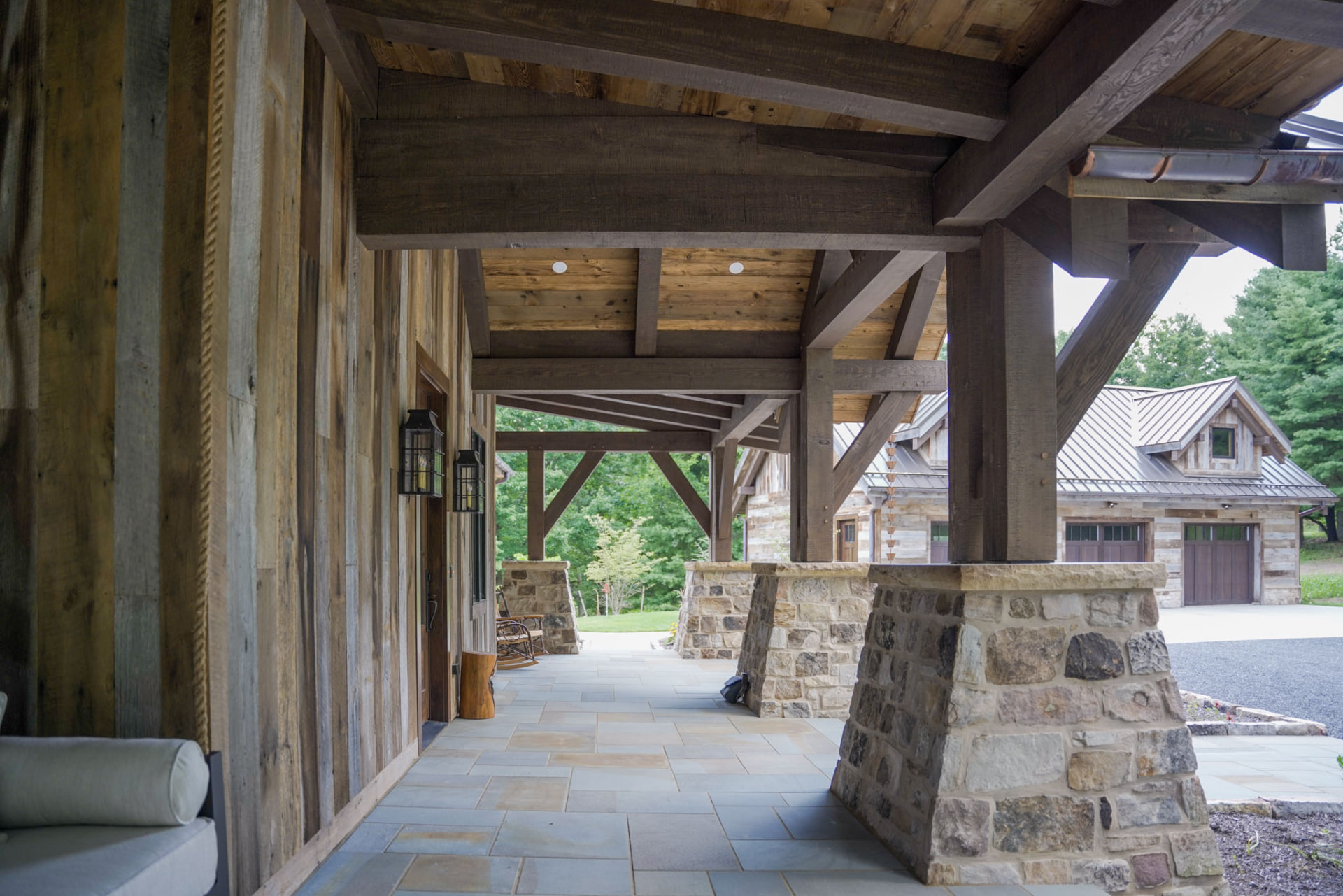 Wright Residence — covered breezeway with massive timber trusses and stone piers on a flagstone terrace — KB Builders, Central Pennsylvania