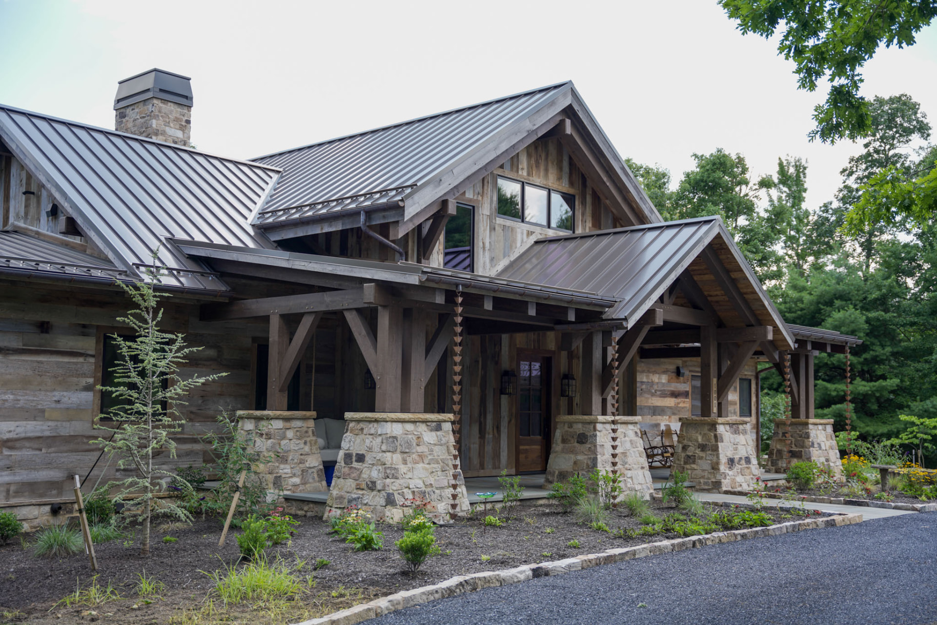 Wright Residence — front three-quarter view with layered metal roofs, timber trusses, and stone piers — KB Builders, Central Pennsylvania
