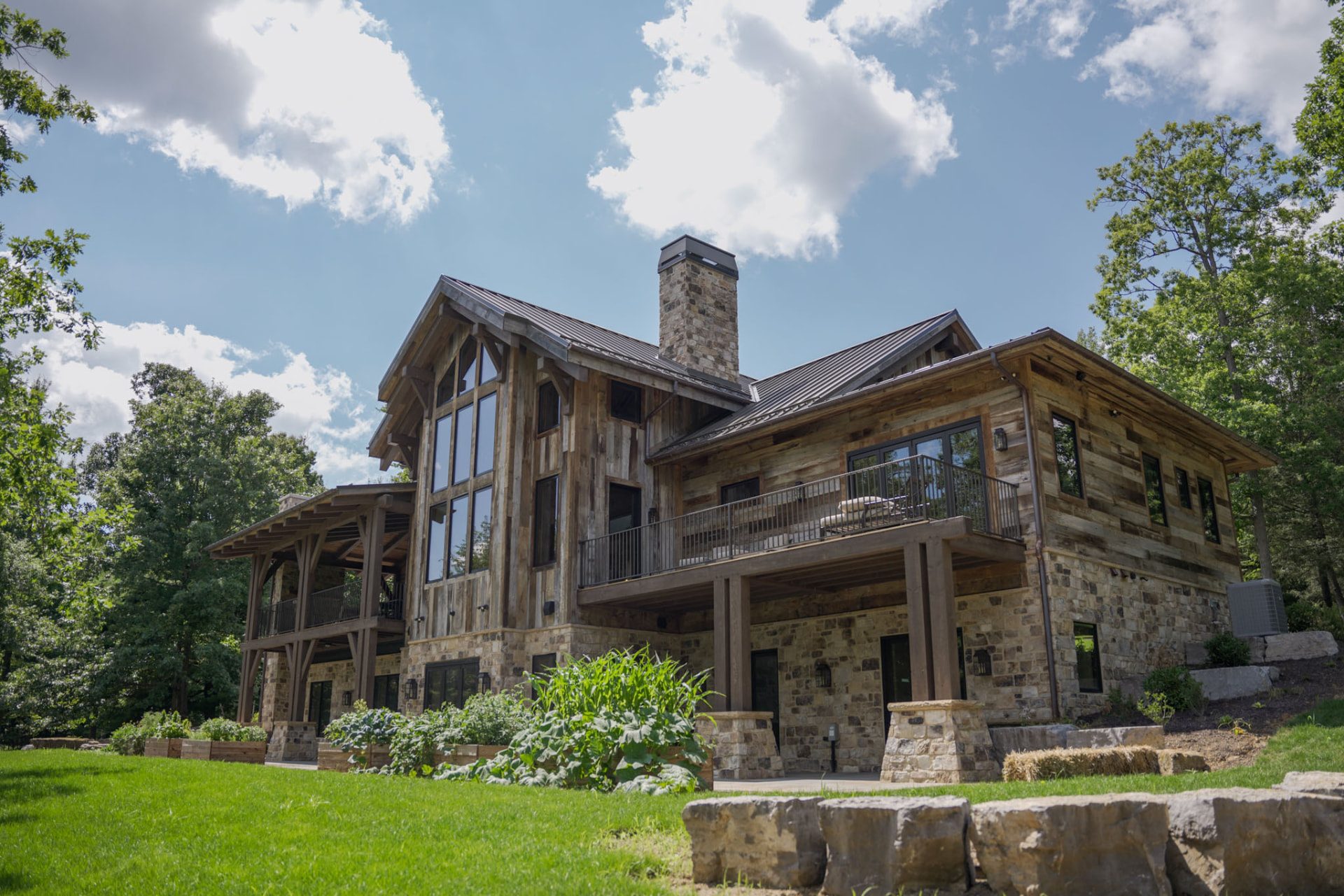 Wright Residence — wide rear view from the lawn with garden beds, stone retaining walls, and covered terraces — KB Builders, Central Pennsylvania