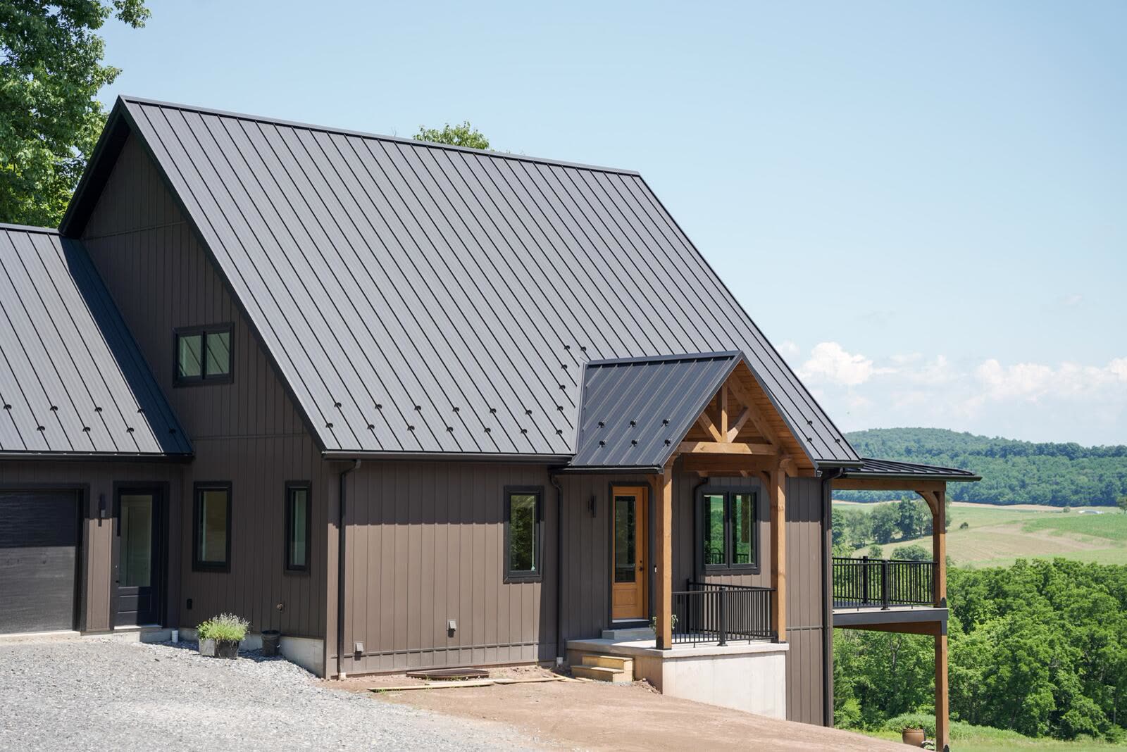 Board-and-batten custom home exterior with black metal roof and timber entry framing valley views — KB Builders, Mifflintown, PA