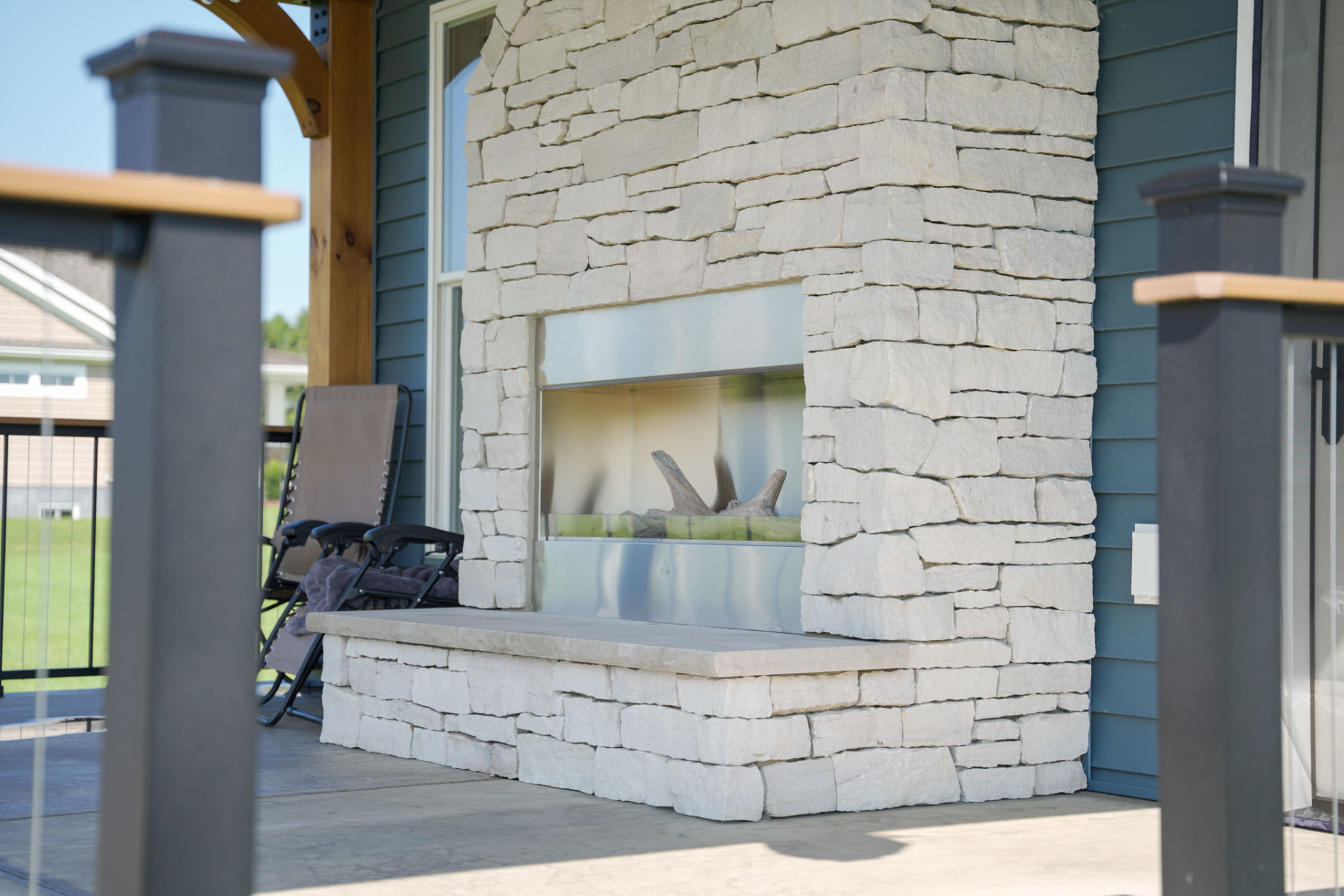 Yoder Residence — outdoor stone fireplace with stone hearth bench on the covered porch — KB Builders, Central Pennsylvania