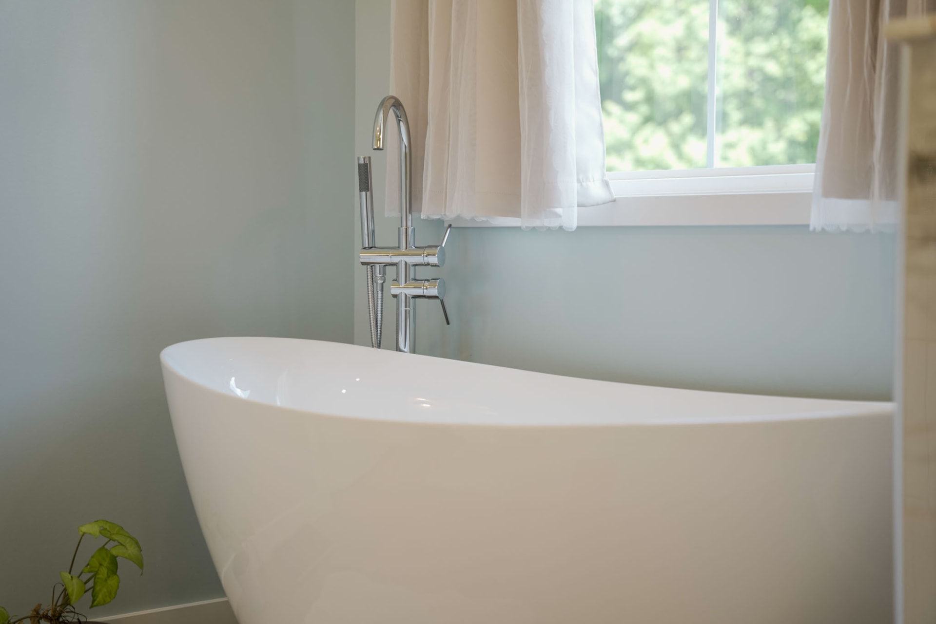 Byler Residence — freestanding soaking tub with chrome floor-mounted filler beneath a bright window — KB Builders, Central Pennsylvania