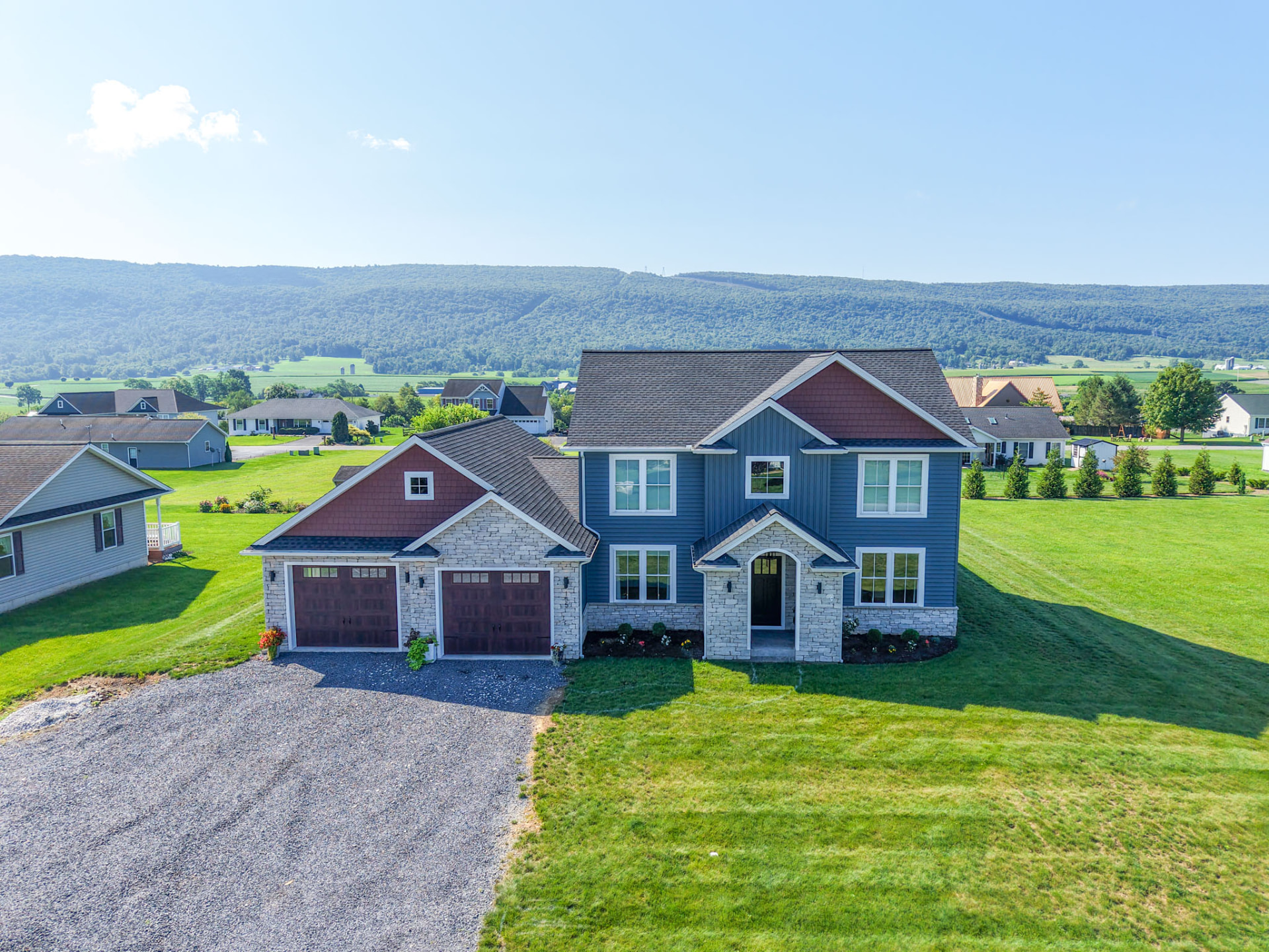 Yoder Residence — aerial angle showing the home's gables, attached garage, and covered side porch with valley views — KB Builders, Central Pennsylvania