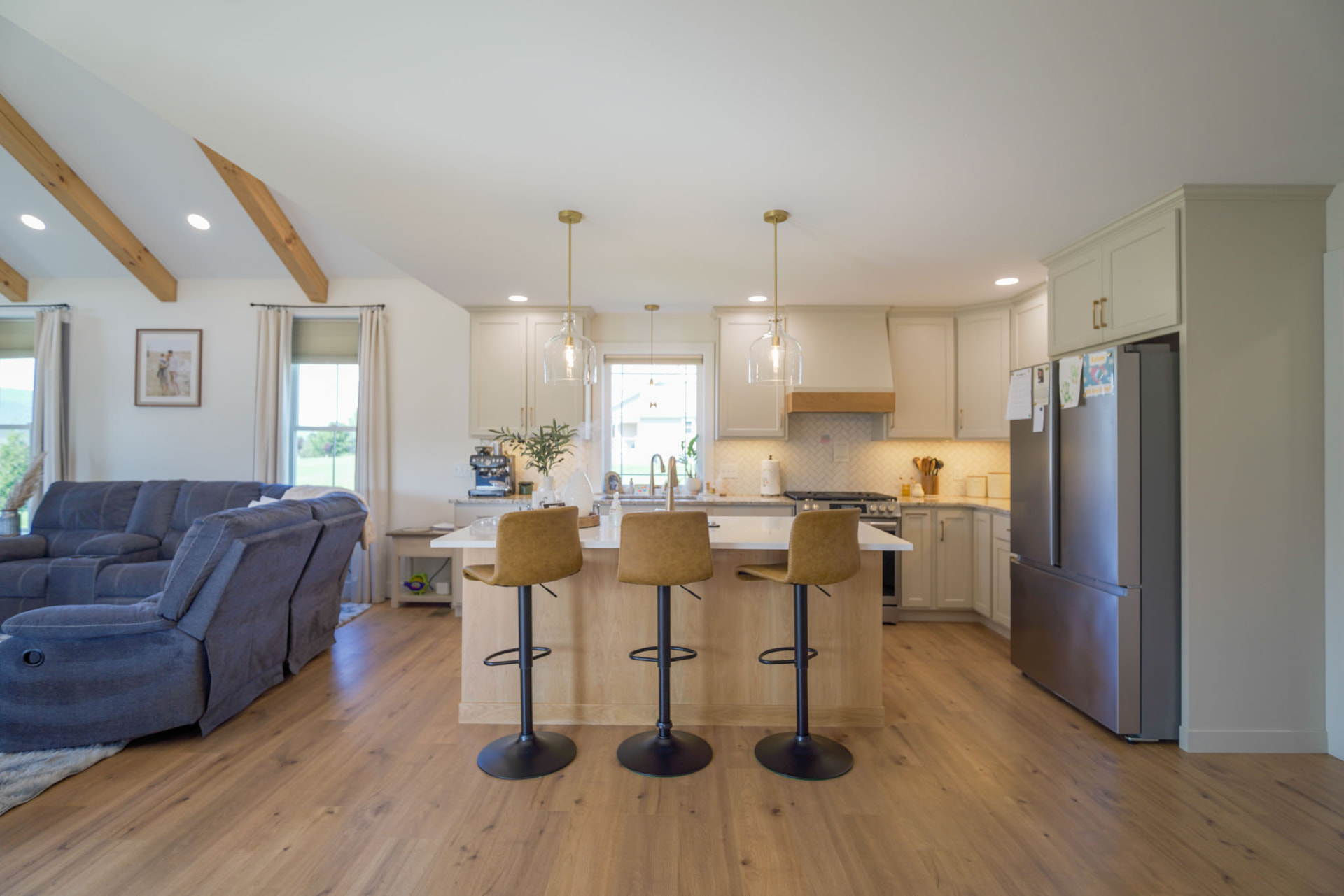 Yoder Residence — kitchen island with leather bar stools looking toward the beamed living area — KB Builders, Central Pennsylvania