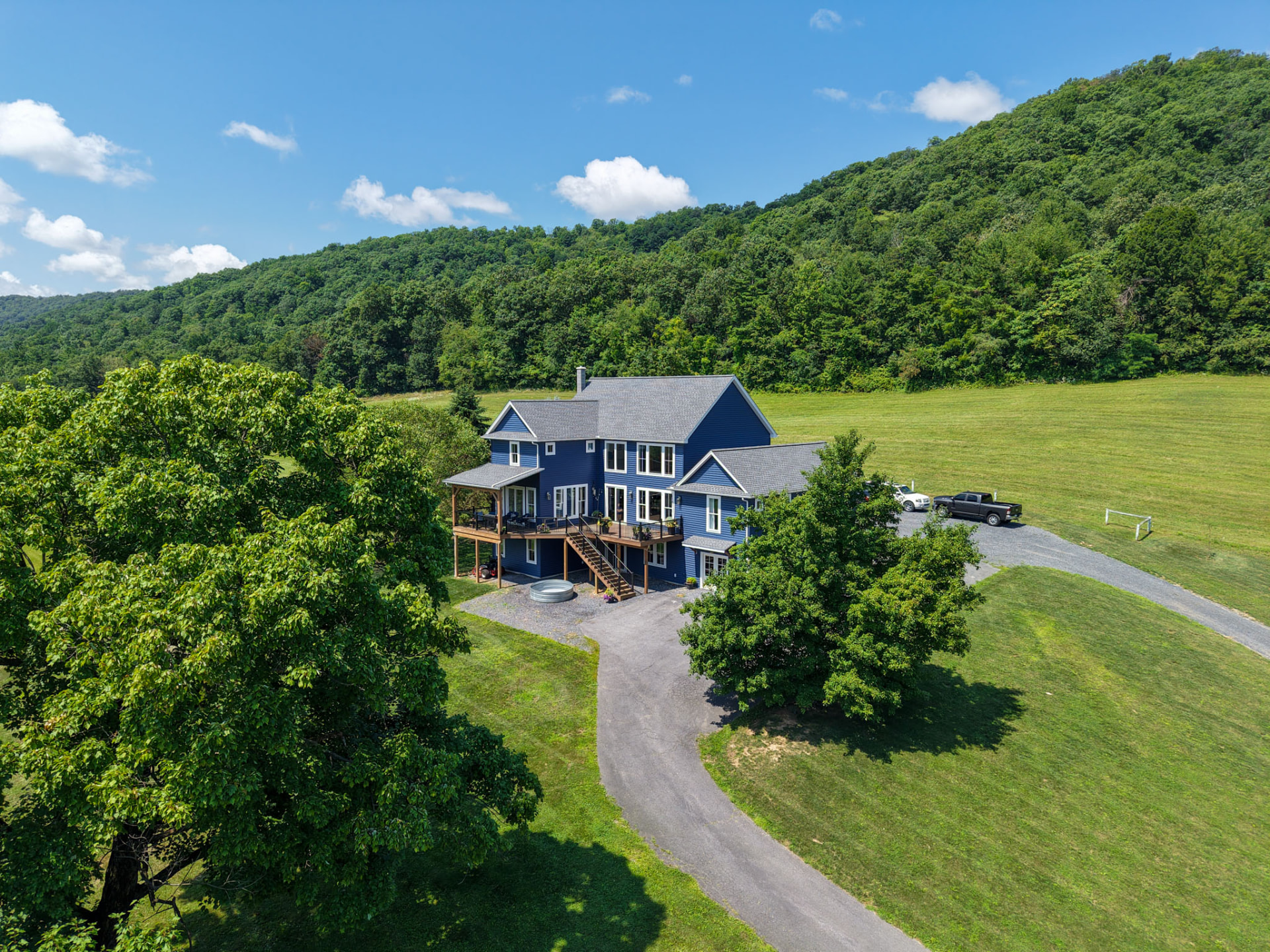 Byler Residence — aerial view of a blue custom home and curved drive set against a wooded ridge — KB Builders, Central Pennsylvania