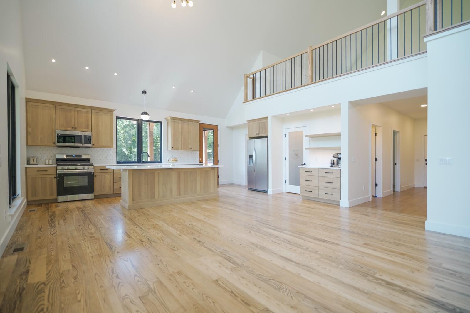 Custom kitchen with light-oak cabinetry, quartz island, and vaulted ceiling opening to the great room — KB Builders, Mifflintown, PA
