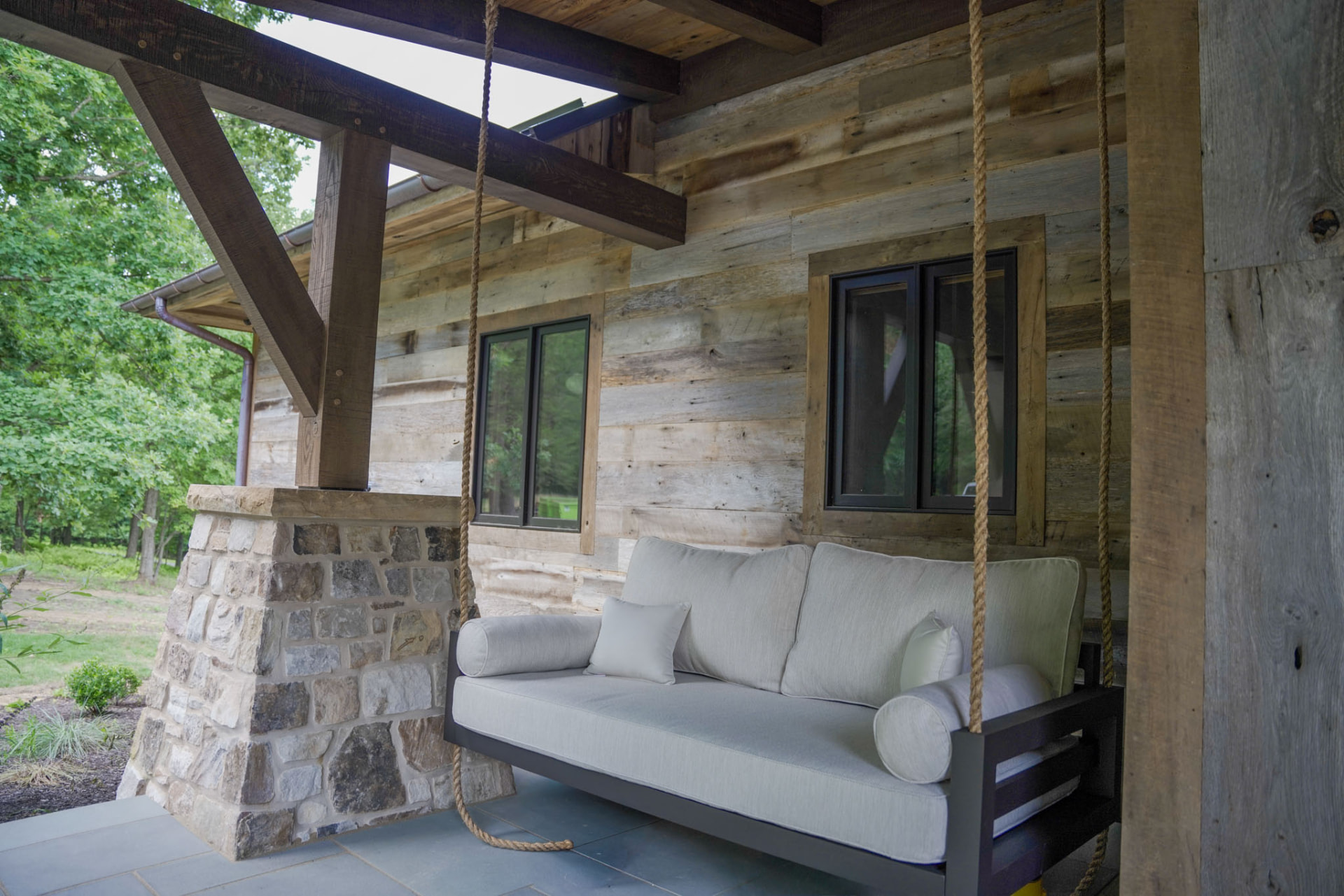 Wright Residence — rope-hung porch swing bed against reclaimed barnwood siding and stone pier — KB Builders, Central Pennsylvania