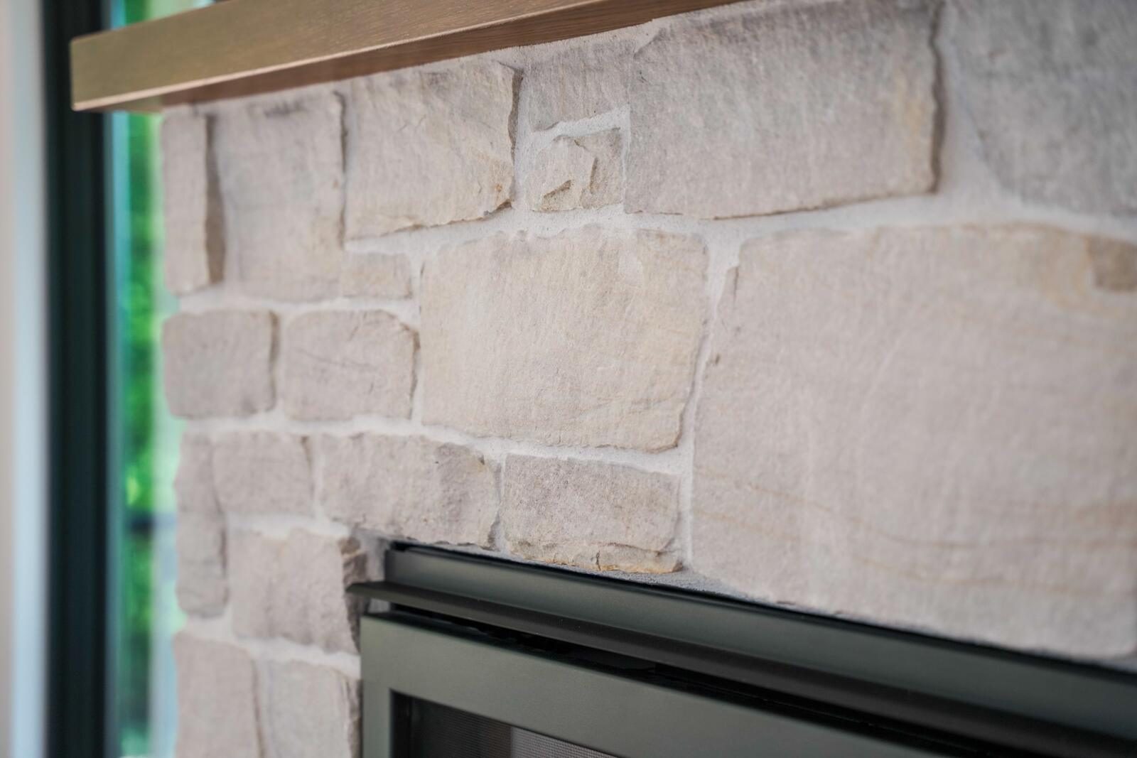 Close-up of hand-laid stacked-stone fireplace masonry with wood mantel — custom home detail by KB Builders, Mifflintown, PA
