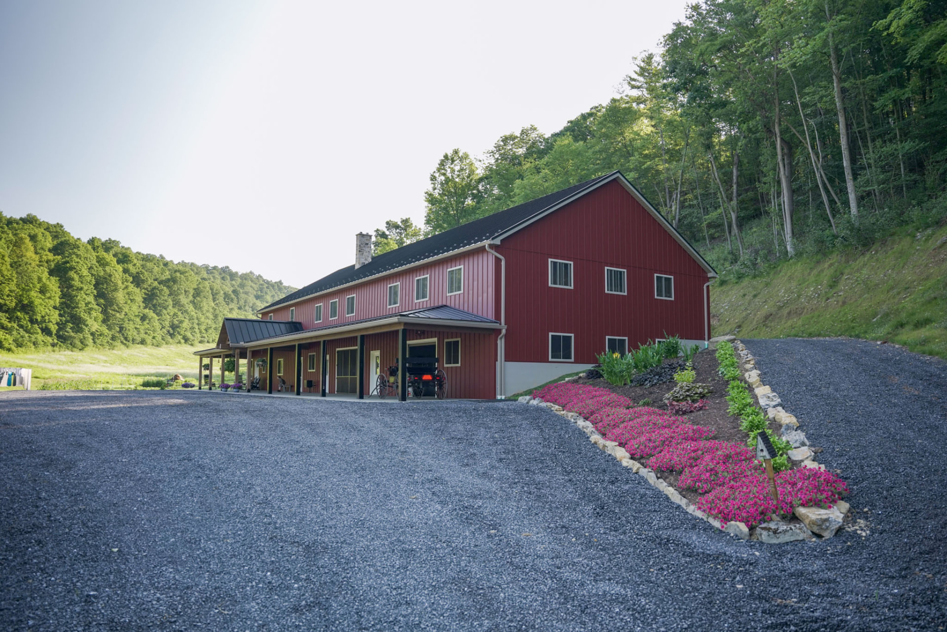 Peachy Residence — front elevation of a red barndominium with long covered porch and gravel drive — KB Builders, McVeytown, PA