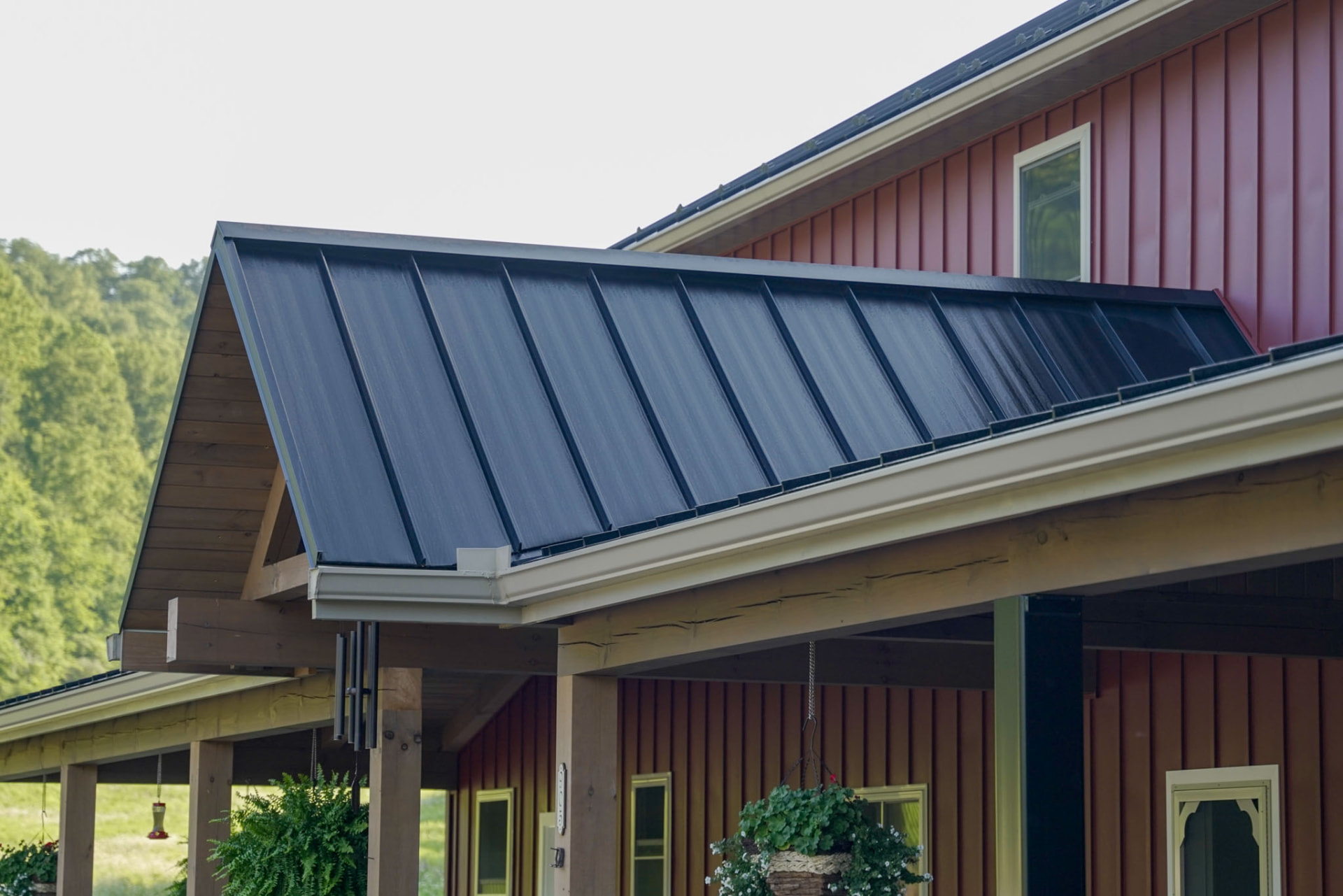 Peachy Residence — black standing-seam metal roof gable and timber porch framing on a barndominium by KB Builders, McVeytown, PA