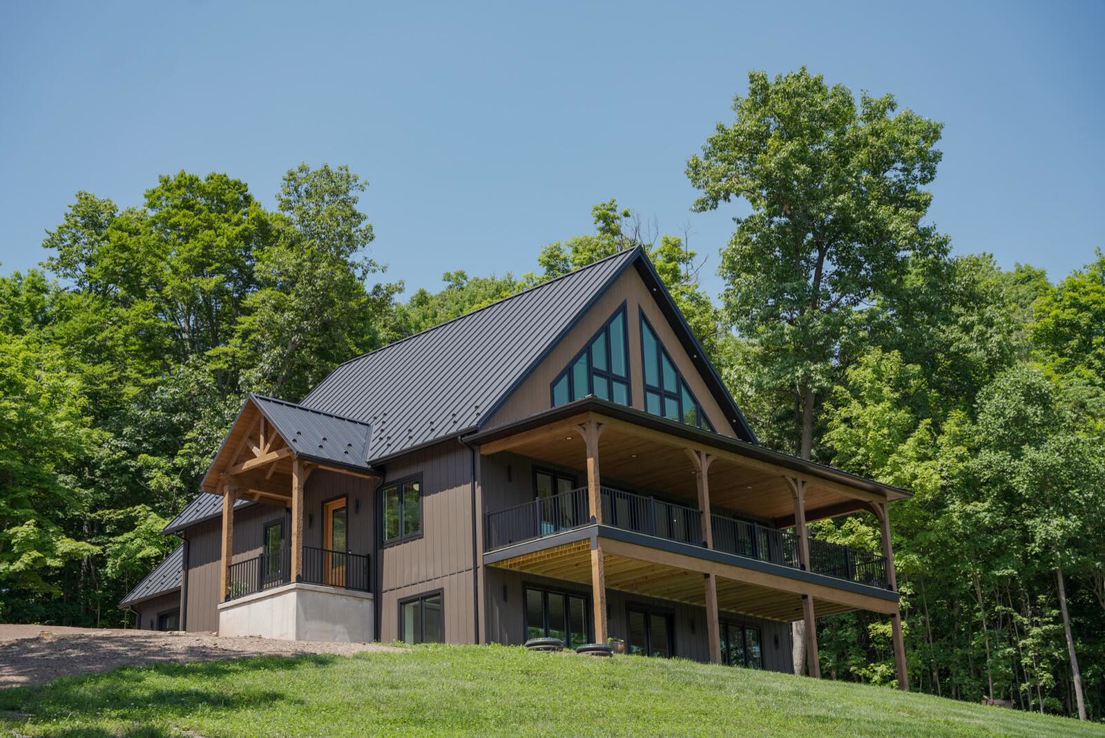Custom home with dark board-and-batten siding and standing-seam metal roof set into the hillside — KB Builders, Mifflintown, PA
