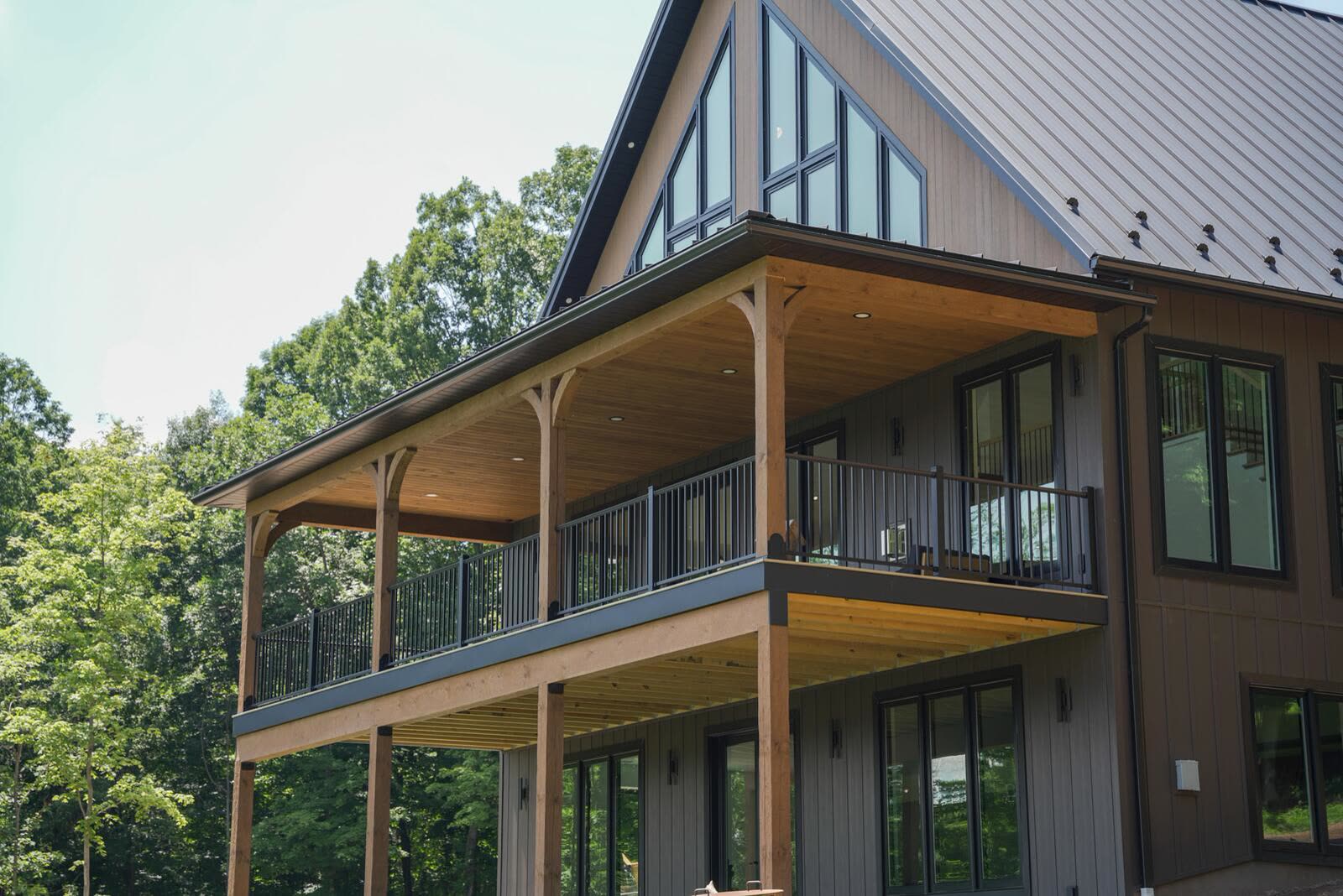 Detail of two-story covered porch with timber posts and black metal railings — Shetler Residence by KB Builders