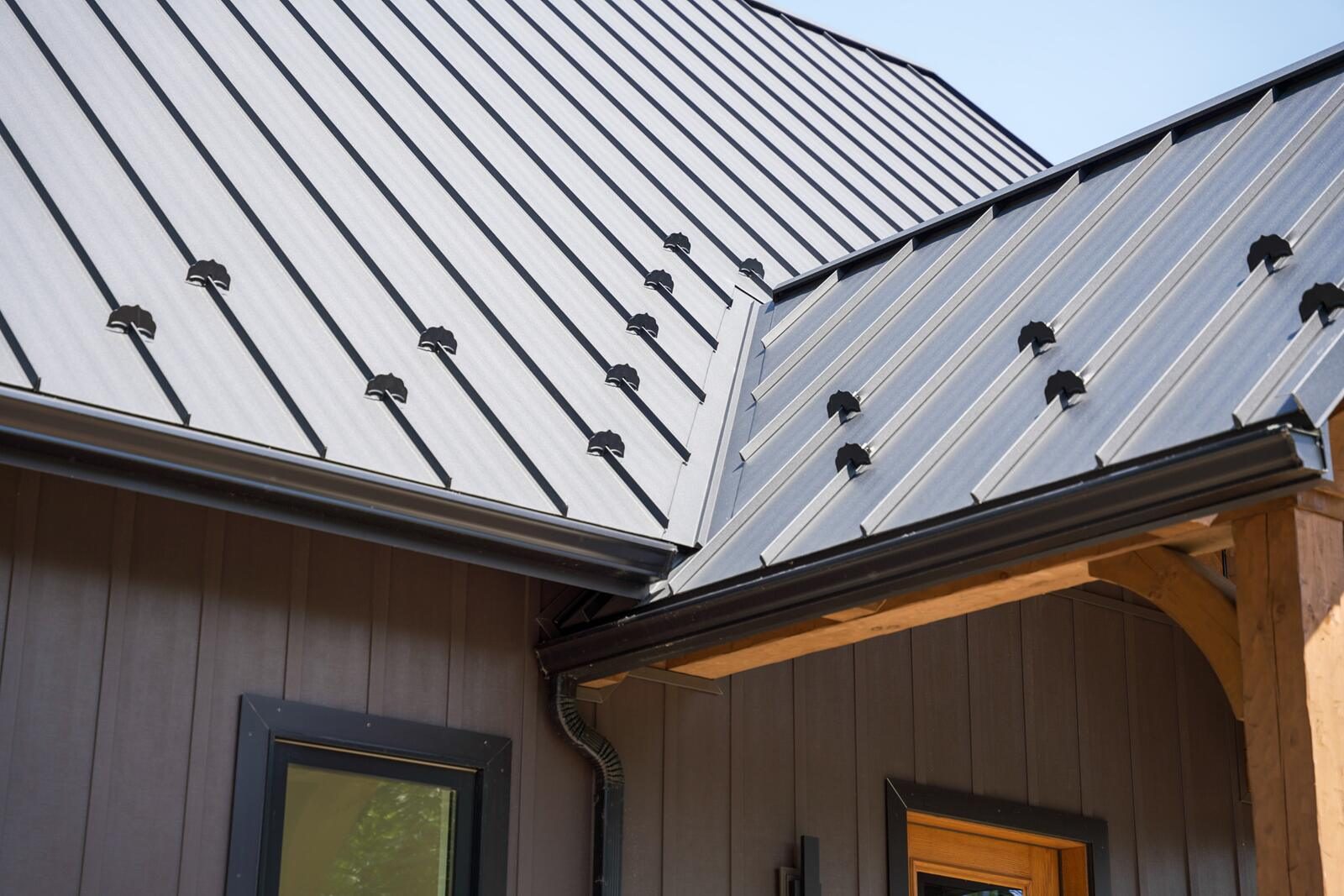 Standing-seam metal roof detail with snow guards and timber-frame porch bracket — custom home by KB Builders, Mifflintown, PA