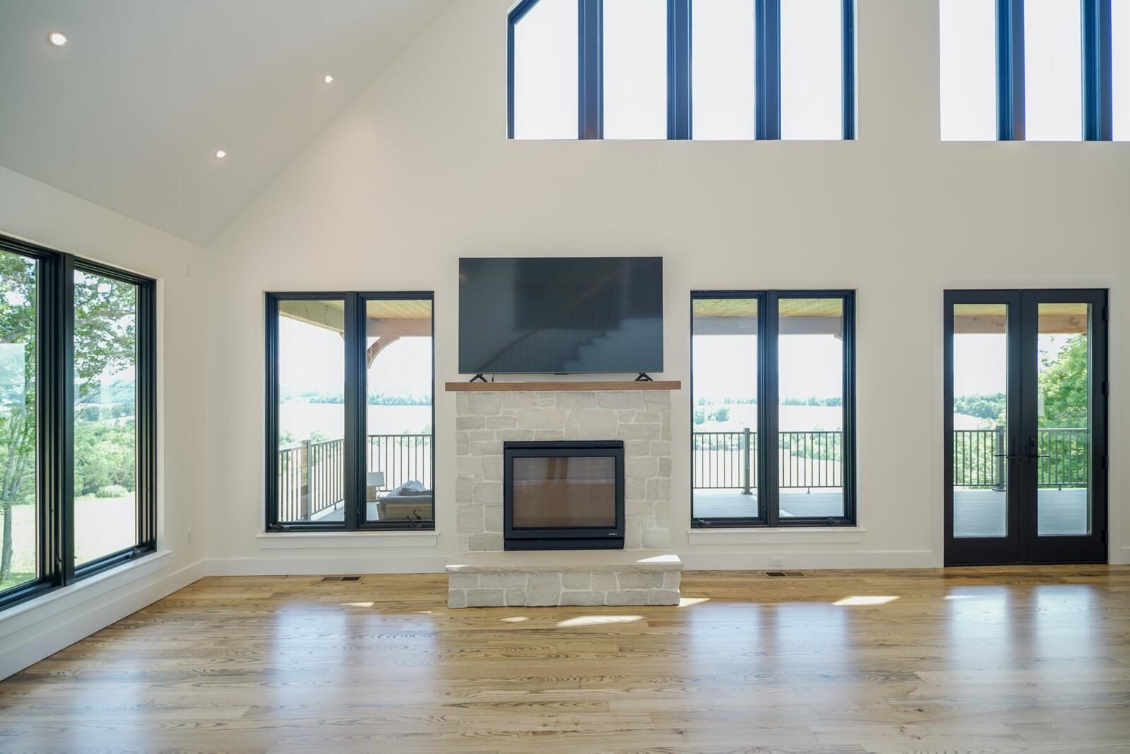 Vaulted great room with stacked-stone fireplace and floor-to-ceiling gable windows in a custom KB Builders home, Mifflintown, PA