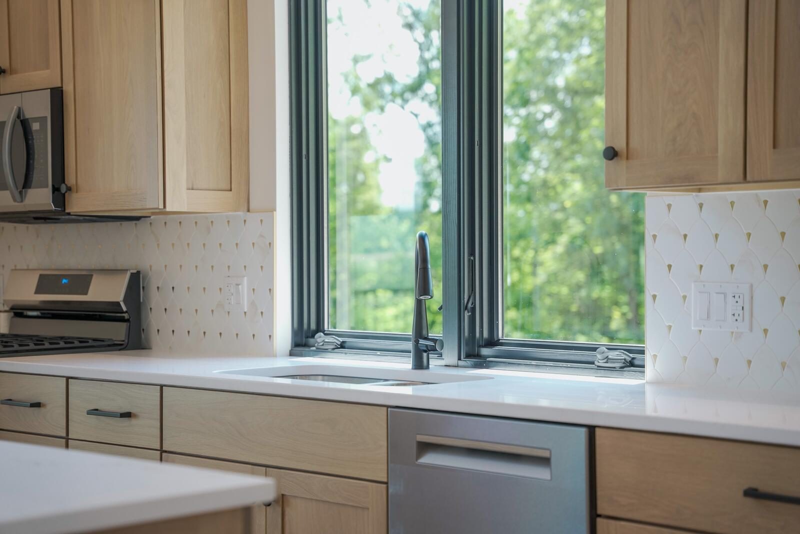 Kitchen detail with quartz counters, custom tile backsplash, and black-framed windows over the sink — KB Builders, Mifflintown, PA