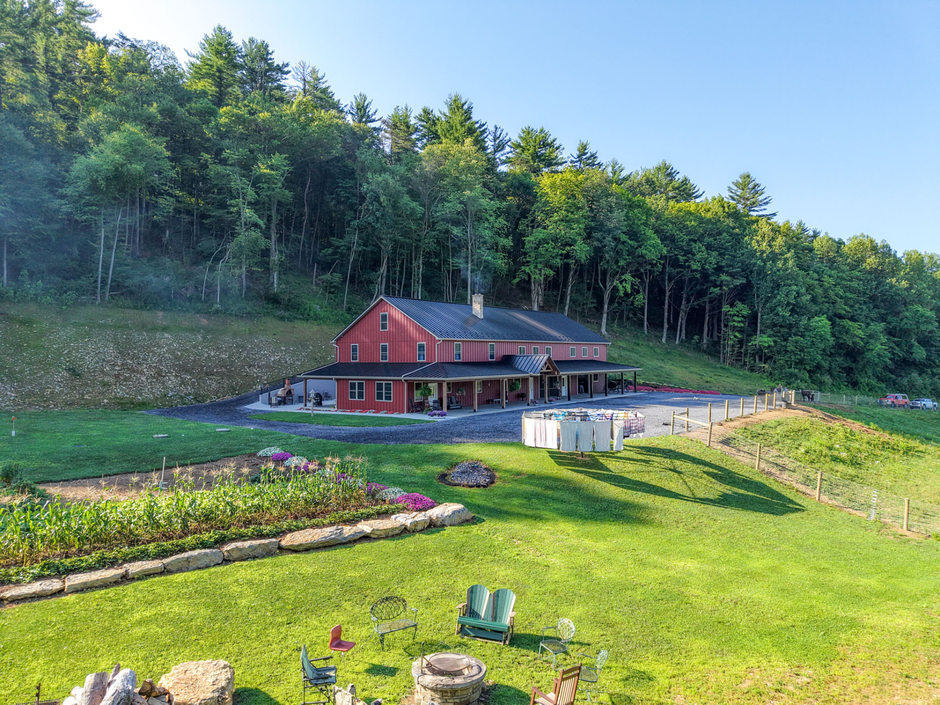 Peachy Residence — barndominium set against wooded hillside with garden, lawn, and fire pit — KB Builders, McVeytown, PA