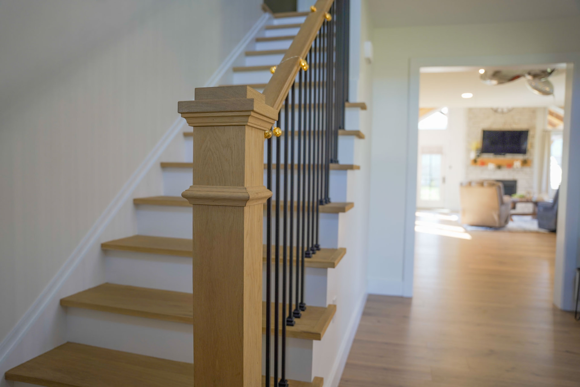 Yoder Residence — white oak staircase with square newel post, iron balusters, and view into the great room — KB Builders, Central Pennsylvania