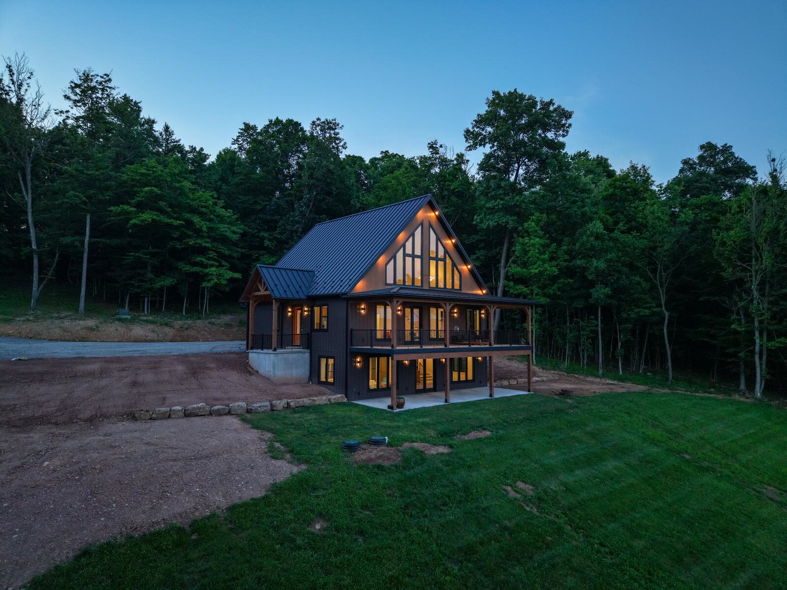 Shetler Residence rear elevation at dusk with covered porch and glowing windows — custom home by KB Builders, Mifflintown, PA