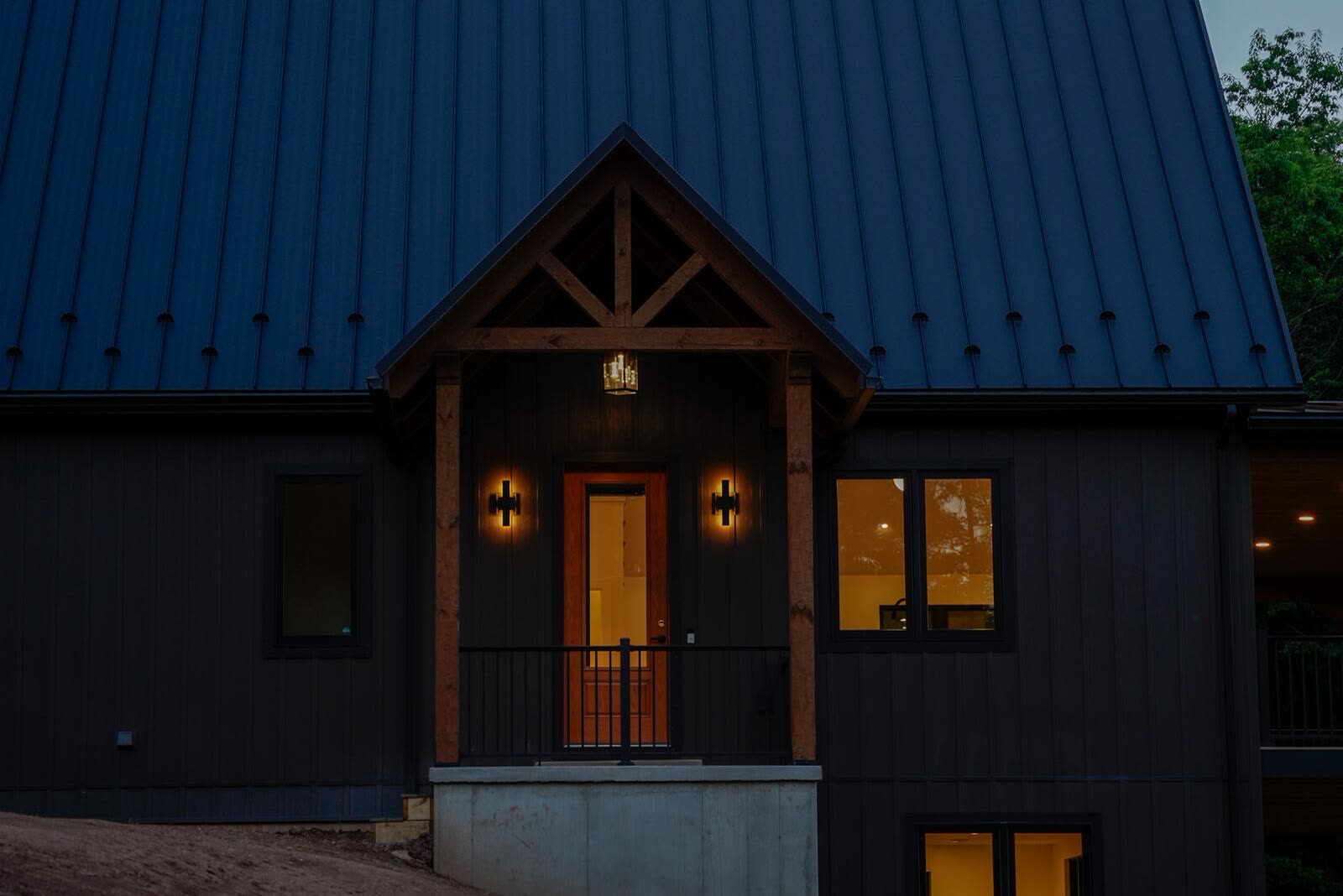 Front entry of a custom home at dusk with timber portico and warm interior glow — KB Builders, Mifflintown, PA