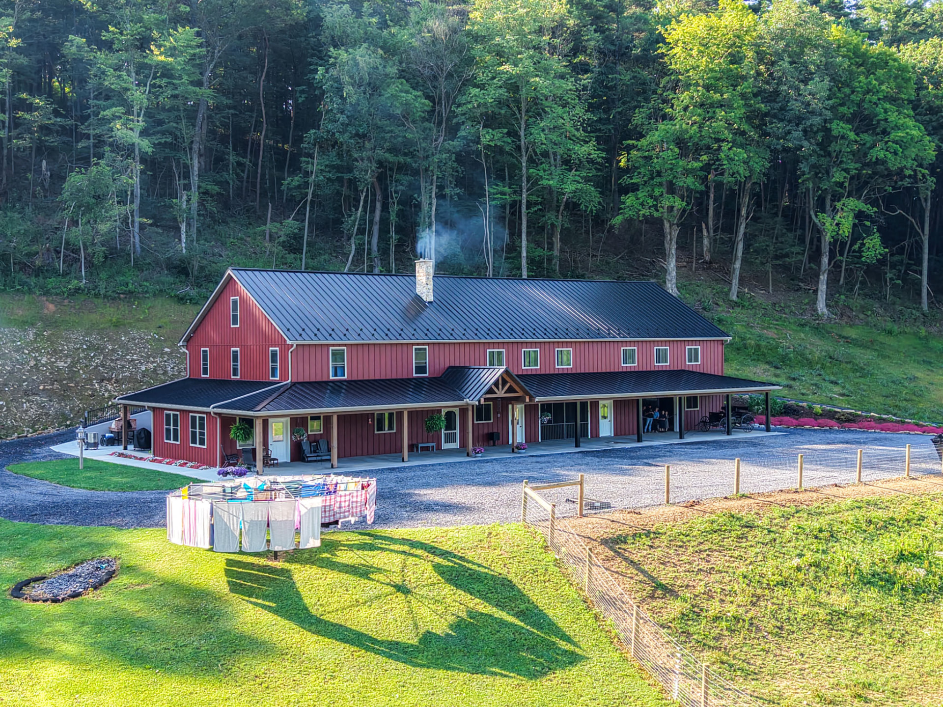 Peachy Residence barndominium with black metal roof and wraparound porch by KB Builders, McVeytown, PA