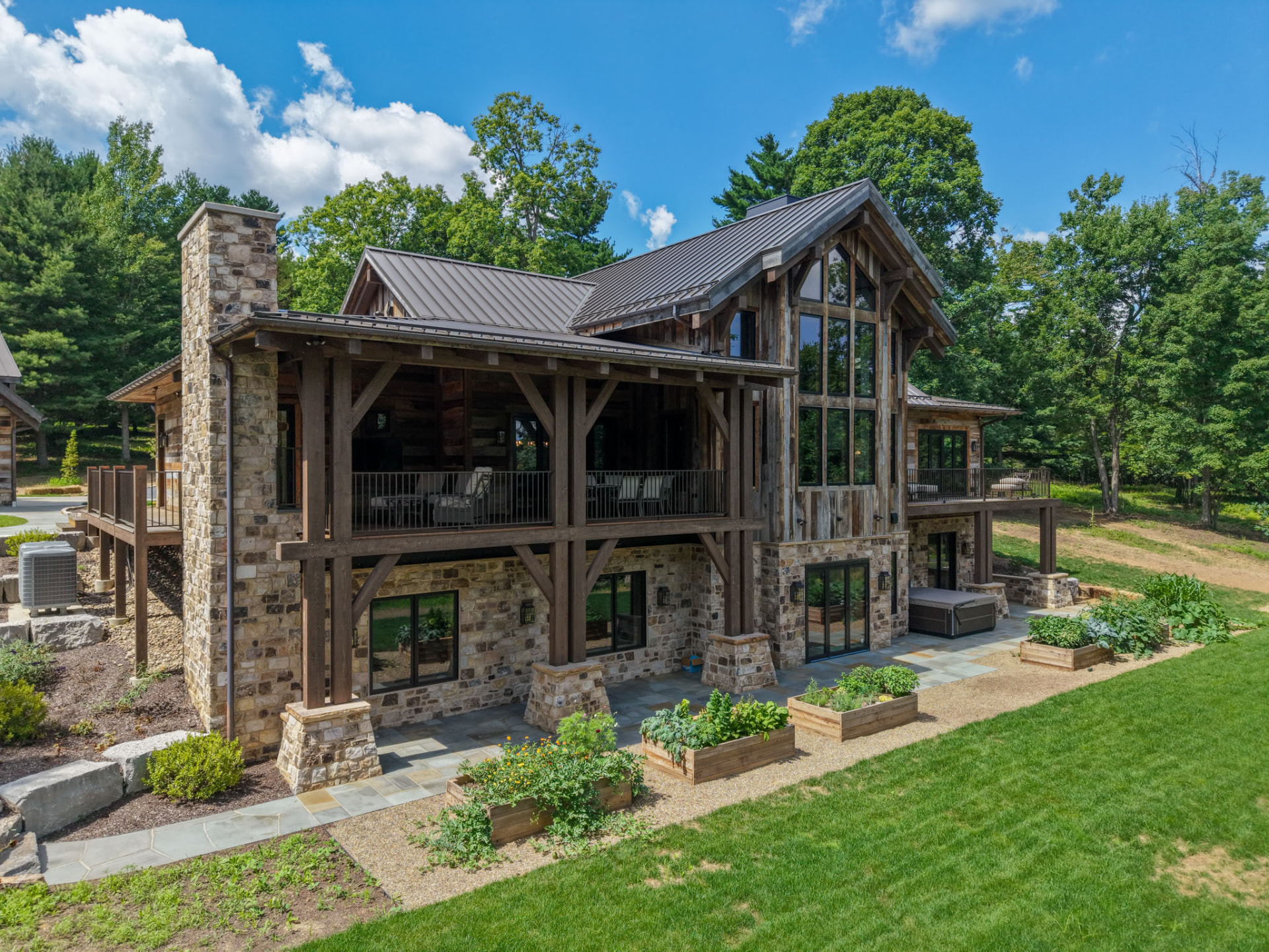 Wright Residence timber-frame framing with stone chimney, reclaimed barnwood siding, and raised garden beds by KB Builders, Central Pennsylvania